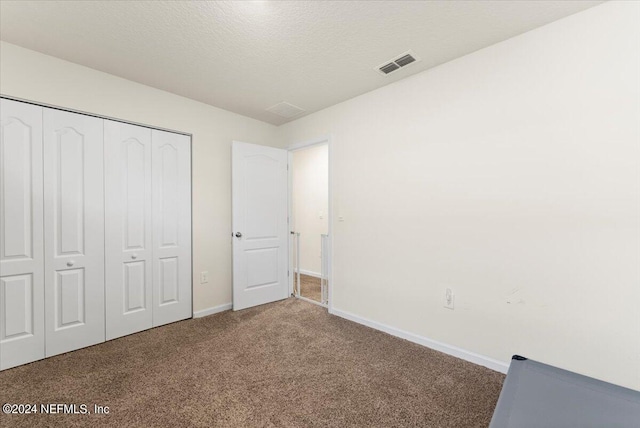 unfurnished bedroom featuring a closet, carpet, and a textured ceiling