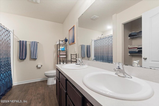 bathroom with hardwood / wood-style flooring, toilet, curtained shower, vanity, and a textured ceiling