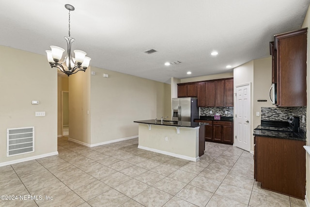 kitchen featuring a center island with sink, appliances with stainless steel finishes, tasteful backsplash, an inviting chandelier, and hanging light fixtures