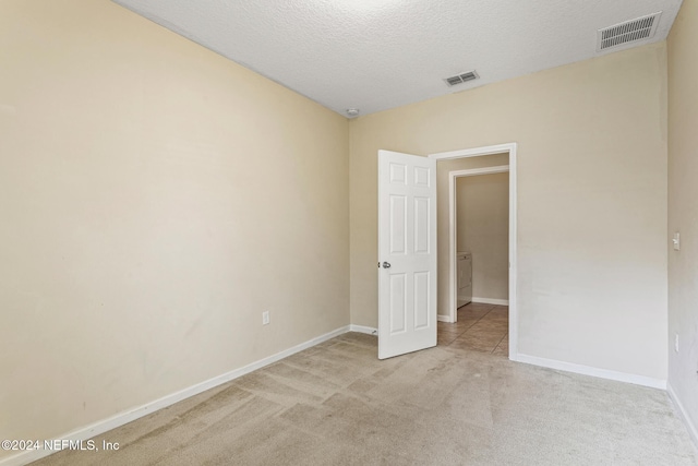 unfurnished bedroom featuring a textured ceiling and light colored carpet