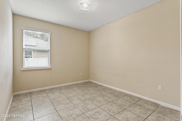 tiled empty room with a textured ceiling