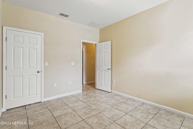 spare room featuring a textured ceiling and light tile patterned floors