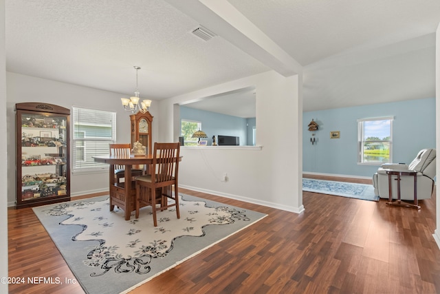 dining space featuring dark wood-type flooring, a textured ceiling, and an inviting chandelier