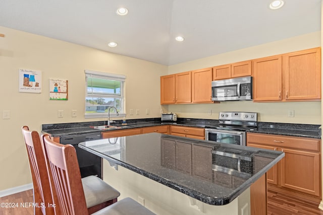 kitchen featuring a kitchen island, a kitchen breakfast bar, light hardwood / wood-style flooring, sink, and appliances with stainless steel finishes