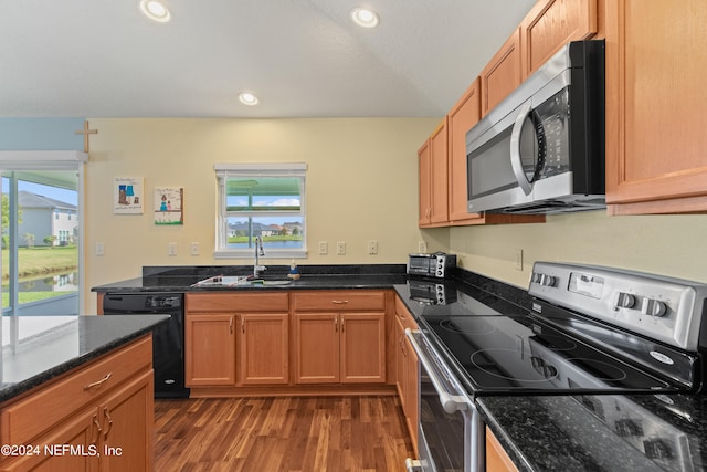 kitchen with dark stone countertops, appliances with stainless steel finishes, sink, and dark hardwood / wood-style floors