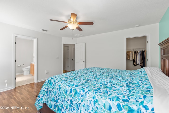 bedroom featuring light wood-type flooring, a walk in closet, ensuite bath, a closet, and ceiling fan