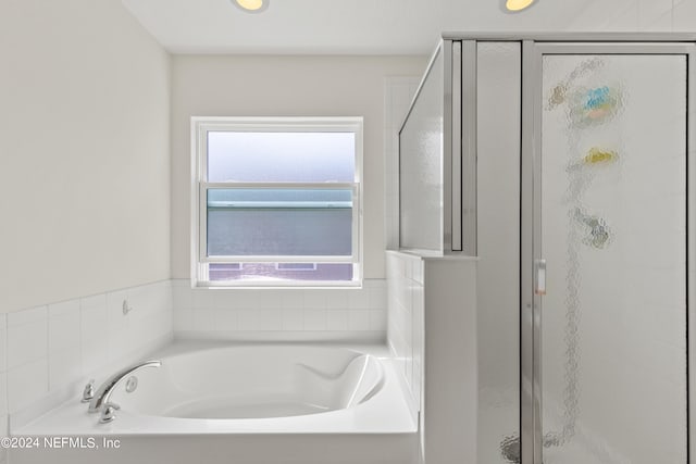 bathroom featuring a healthy amount of sunlight and shower with separate bathtub