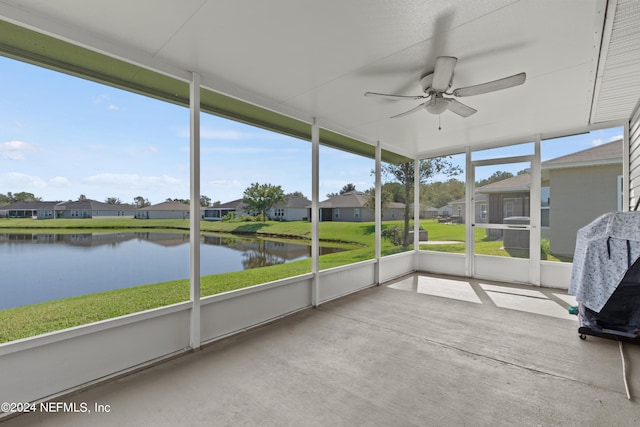 unfurnished sunroom with a healthy amount of sunlight, a water view, and ceiling fan