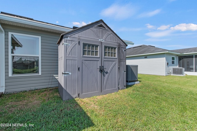 view of outbuilding with a lawn and central AC unit