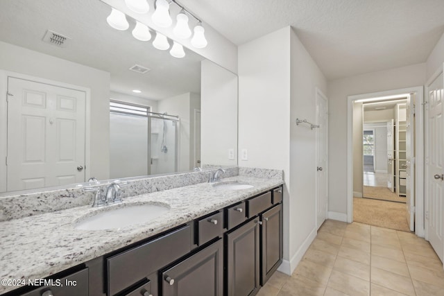 bathroom featuring vanity, a textured ceiling, tile patterned flooring, and an enclosed shower