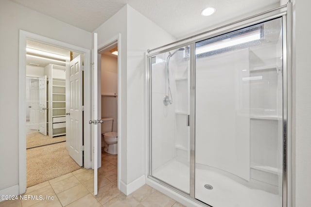 bathroom featuring tile patterned flooring, toilet, and a shower with door