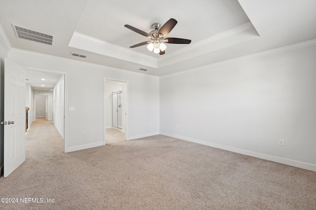 spare room with light carpet, a tray ceiling, ornamental molding, and ceiling fan