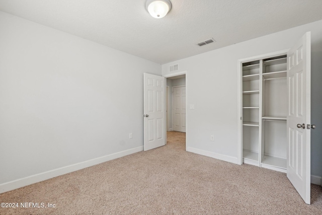 unfurnished bedroom featuring carpet floors, a closet, and a textured ceiling