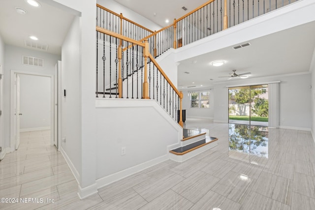 staircase with ornamental molding and ceiling fan