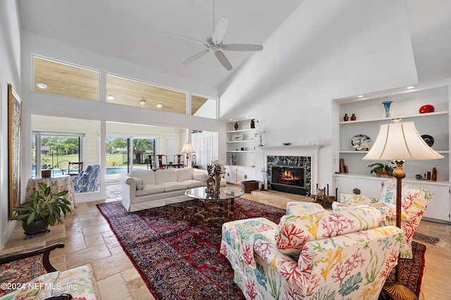 living room featuring a fireplace, built in features, high vaulted ceiling, and ceiling fan