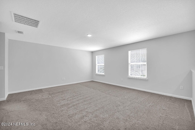 empty room with a textured ceiling and carpet flooring