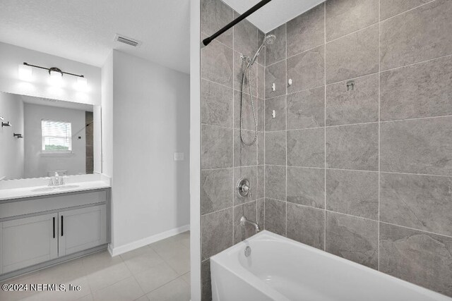 bathroom featuring tile patterned floors, vanity, and tiled shower / bath