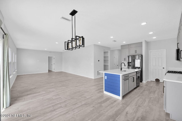 kitchen with pendant lighting, an island with sink, light hardwood / wood-style flooring, and gray cabinetry