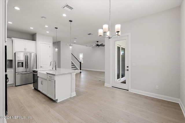 kitchen with a center island with sink, ceiling fan with notable chandelier, white cabinets, and appliances with stainless steel finishes