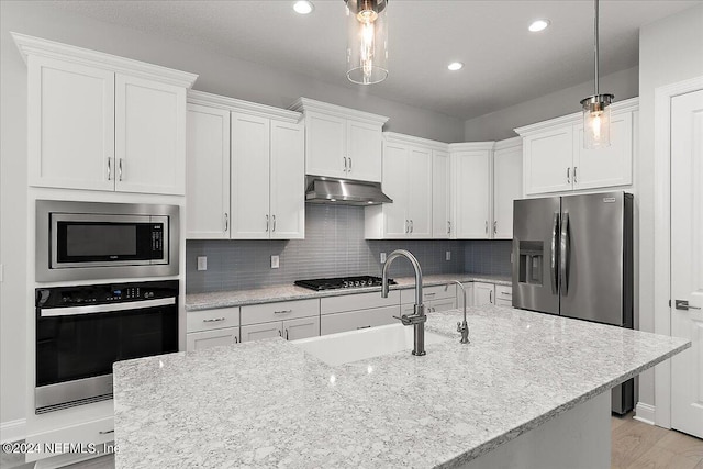 kitchen featuring sink, decorative light fixtures, white cabinetry, appliances with stainless steel finishes, and light hardwood / wood-style floors