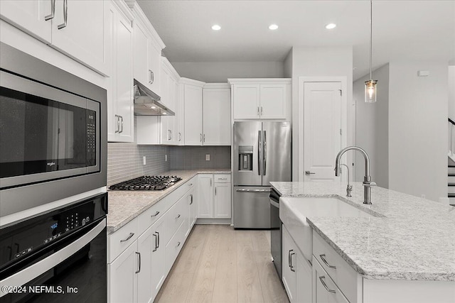 kitchen featuring an island with sink, stainless steel appliances, white cabinets, light hardwood / wood-style floors, and range hood