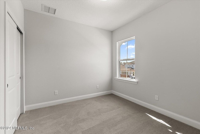 unfurnished bedroom featuring a closet, carpet flooring, and a textured ceiling