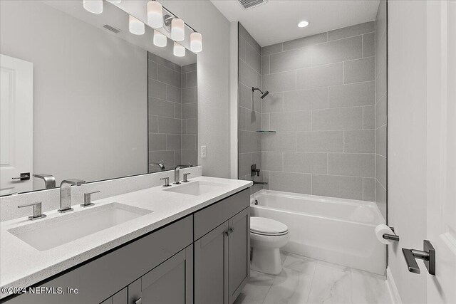 full bathroom with tiled shower / bath combo, vanity, and toilet