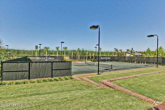 view of tennis court featuring a lawn