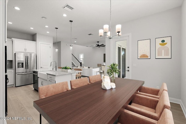 dining area with ceiling fan with notable chandelier and light wood-type flooring