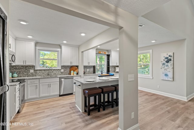 kitchen with a healthy amount of sunlight, appliances with stainless steel finishes, and white cabinetry