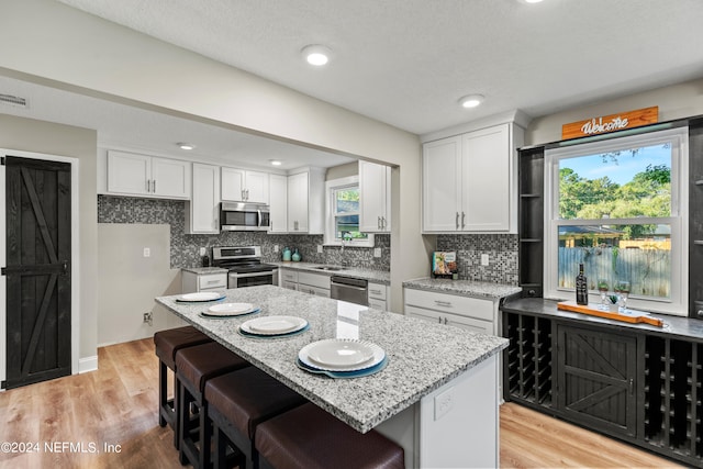 kitchen with appliances with stainless steel finishes, white cabinetry, and plenty of natural light