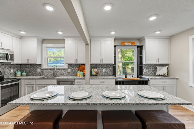 kitchen featuring white cabinetry, a center island, stainless steel appliances, and a breakfast bar area