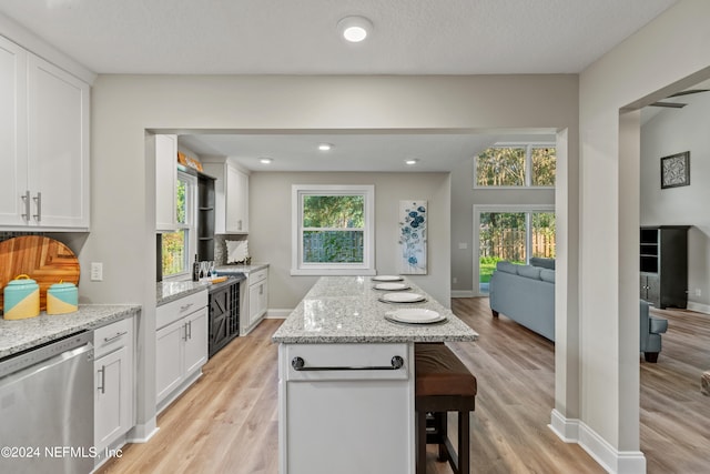 kitchen with dishwasher, a center island, white cabinetry, and light hardwood / wood-style floors