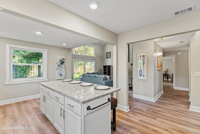 kitchen featuring white cabinets, light wood-type flooring, and a wealth of natural light