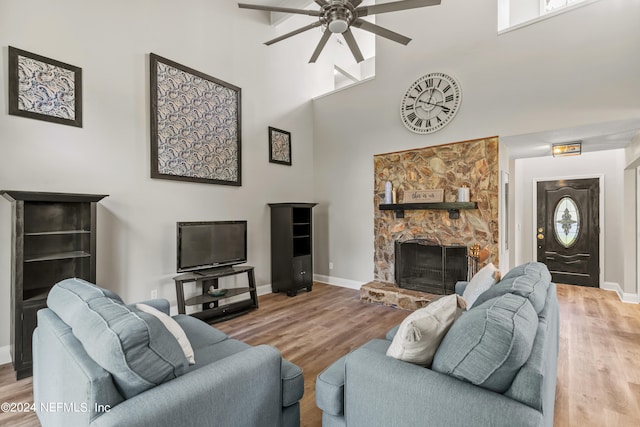 living room featuring a high ceiling, a fireplace, hardwood / wood-style flooring, and ceiling fan