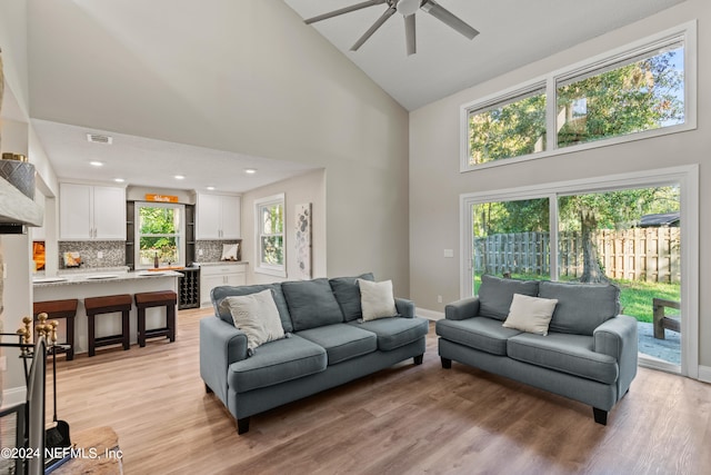 living room with ceiling fan, high vaulted ceiling, light hardwood / wood-style flooring, and wine cooler