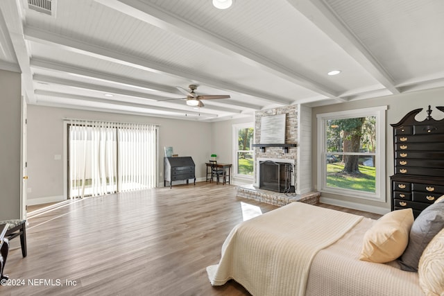 bedroom with beam ceiling, hardwood / wood-style flooring, a fireplace, and ceiling fan