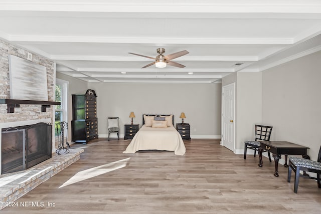 bedroom featuring ceiling fan, beamed ceiling, light wood-type flooring, and a fireplace