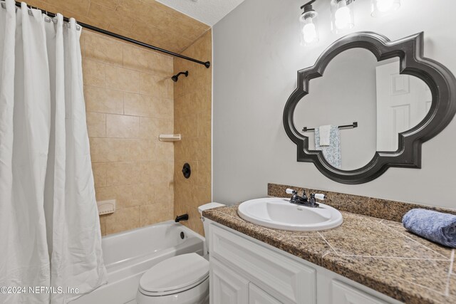 full bathroom with vanity, a textured ceiling, toilet, and shower / bathtub combination with curtain