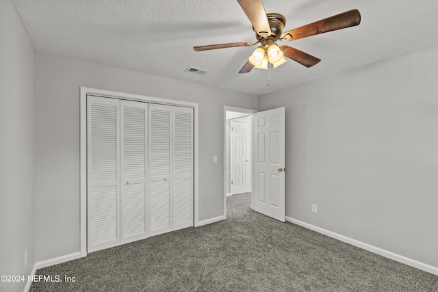 unfurnished bedroom featuring dark colored carpet, a closet, a textured ceiling, and ceiling fan