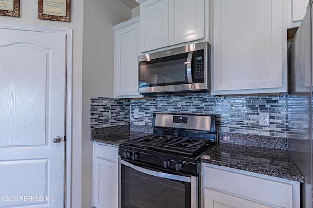 kitchen with dark stone countertops, white cabinets, appliances with stainless steel finishes, and decorative backsplash