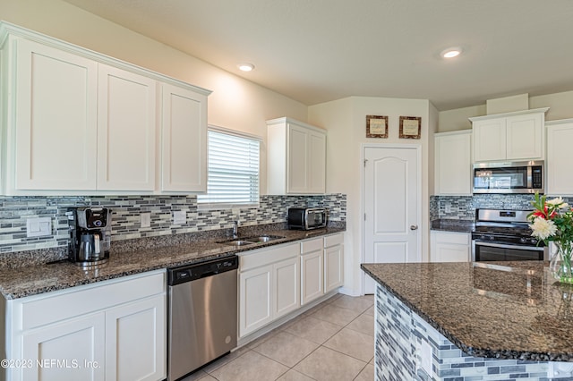 kitchen with dark stone countertops, appliances with stainless steel finishes, sink, and white cabinetry