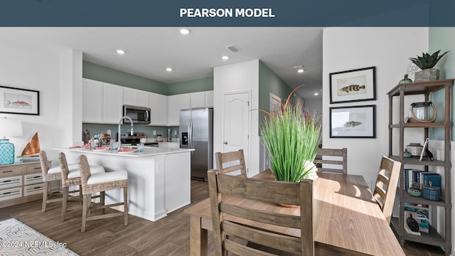 kitchen featuring white cabinets, dark hardwood / wood-style flooring, a breakfast bar area, and appliances with stainless steel finishes