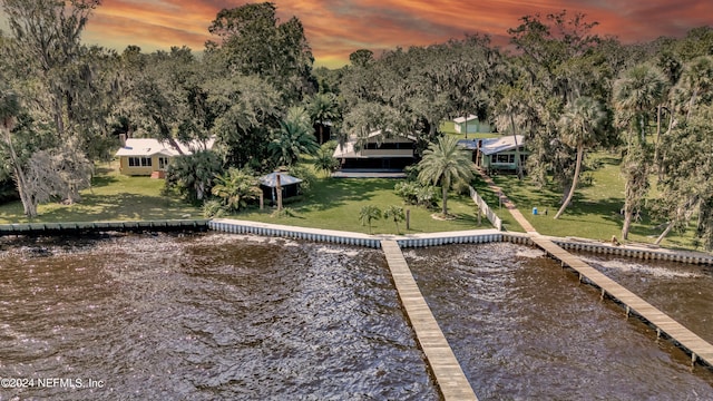 view of dock with a yard and a water view