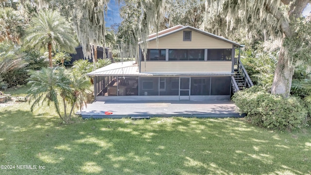 back of property featuring a sunroom and a lawn