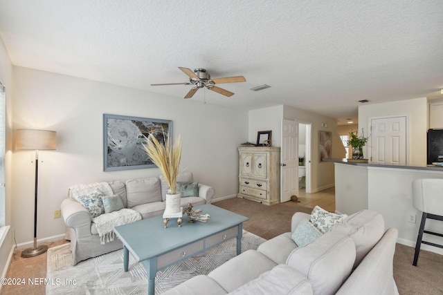 carpeted living room with a textured ceiling and ceiling fan