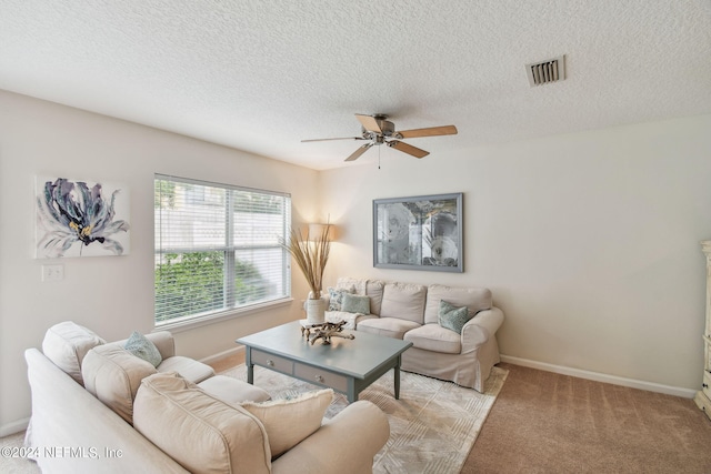 living room with a textured ceiling, ceiling fan, and light colored carpet