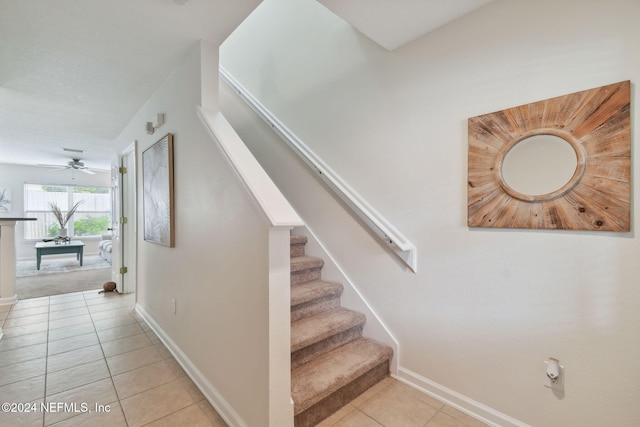 stairs featuring ceiling fan and tile patterned flooring