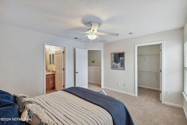 bedroom featuring ceiling fan, light carpet, a spacious closet, a closet, and a textured ceiling