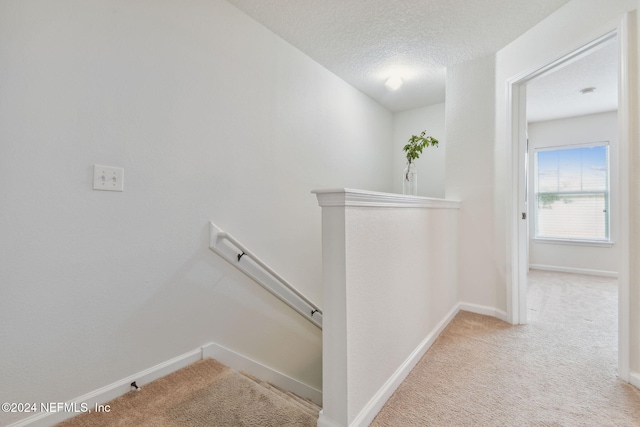 stairs featuring a textured ceiling and carpet